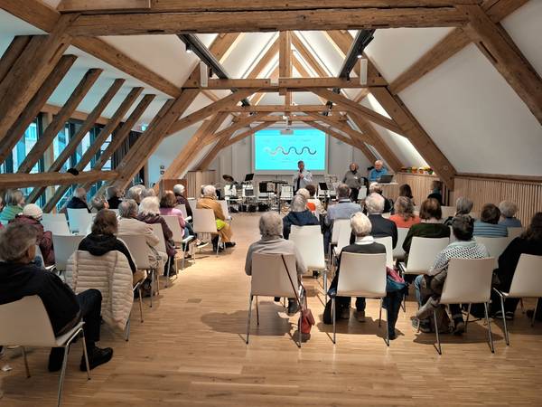 Ansicht Scheunensaal in St. Georgen mit sitzenden Teilnehmenden des Vortrags zum Thema Betrugsprävention